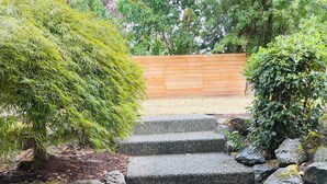Un escalier en pierre menant à une terrasse en bois, entourée de verdure et de rochers.