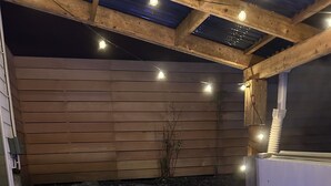 Un bain à remous doté d’un panneau de commande numérique, entouré de murs en bois et d’un mur en pierre.