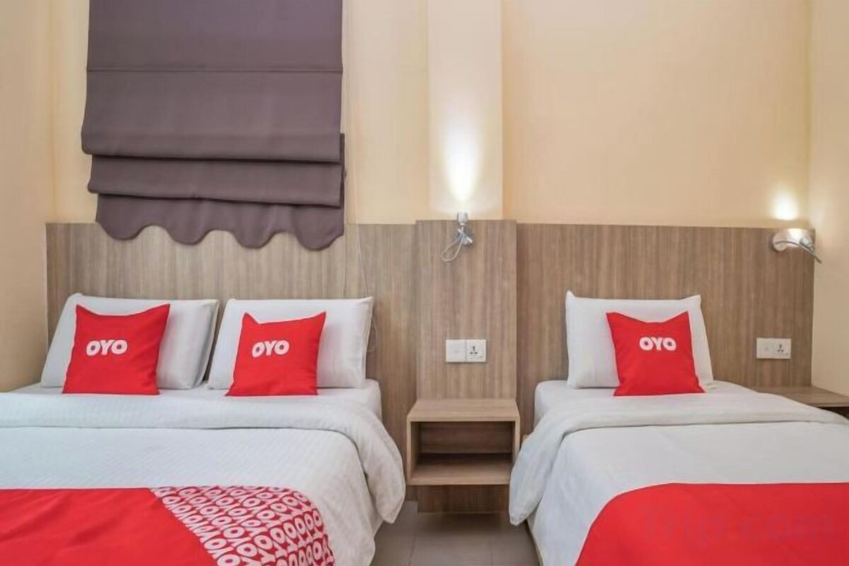 A hotel room with two beds, each with a red and white bedspread and matching pillows.