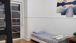 Una habitación con una cama, una mesita, un reloj de pared y un cuadro de un lago.