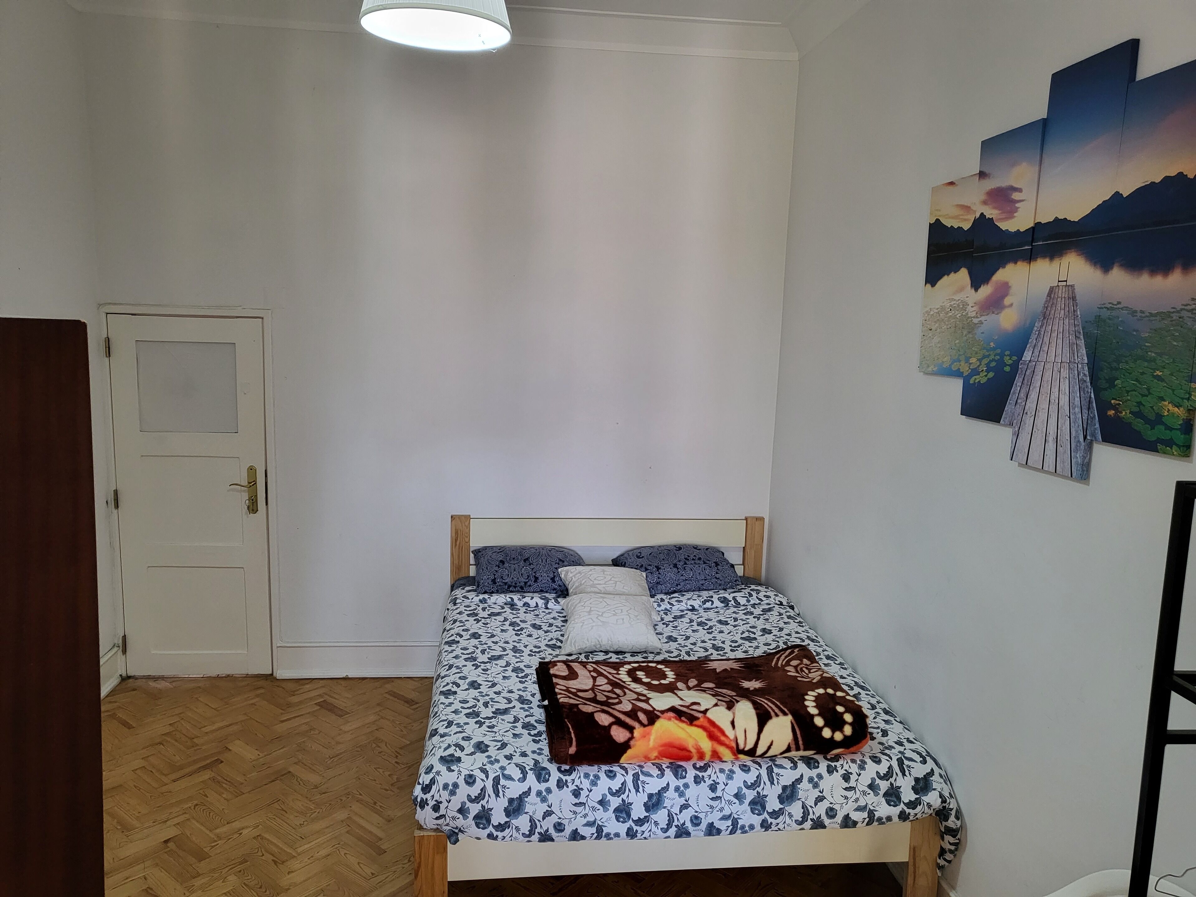A bedroom with a wooden bed, a white door, and a wooden floor.