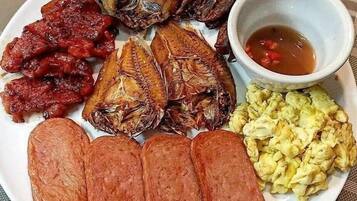 A plate with various food items including fried fish, sausages, and a bowl of sauce.