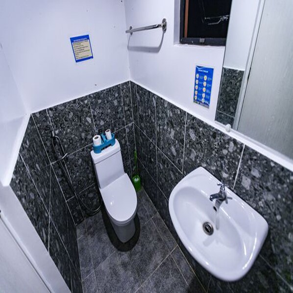 A small bathroom with a toilet, sink, and tiled walls. - LANGOJON JIANJOY RESORT (General Luna)