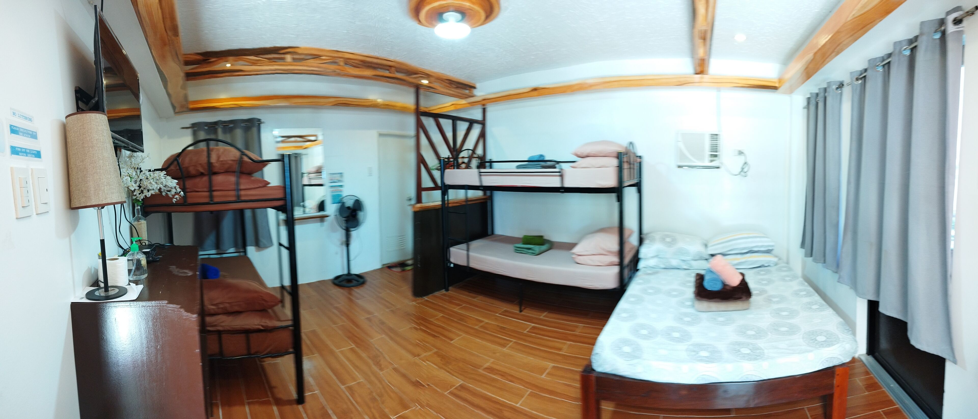 A bunk bed room with a desk, a lamp, and a fan.