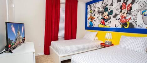 A hotel room with two beds, a TV, a mural, and red curtains.