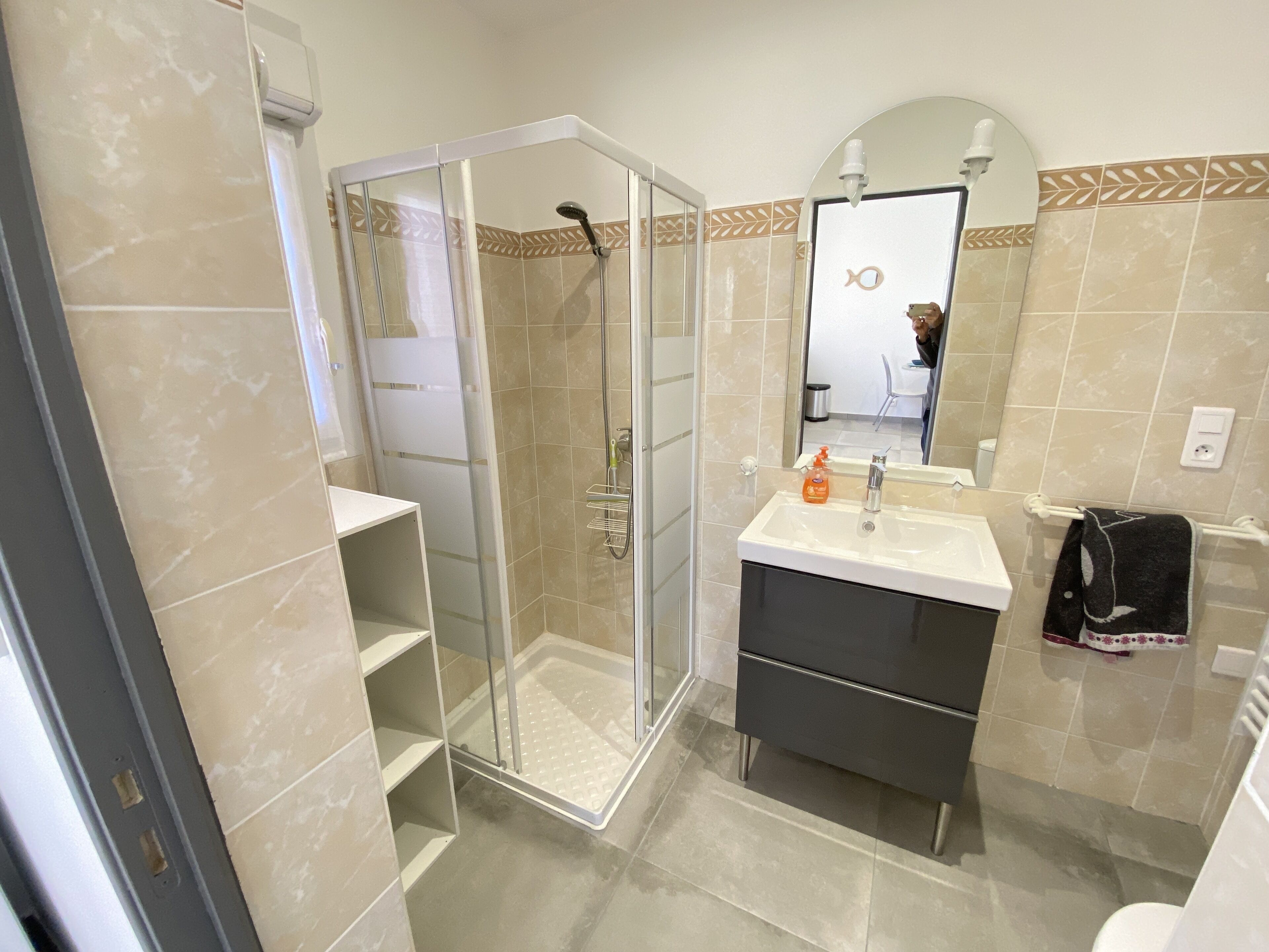 A modern bathroom with a glass shower enclosure, a vanity with a sink, and a towel rack.