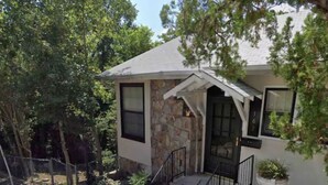 A single-story house with a stone facade, a front porch with a railing, and a small garden area.