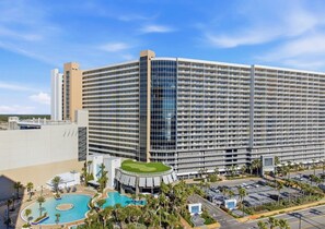 Un grand hôtel avec de nombreux étages, une piscine et un parking.