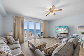 A living room with a television, sofa, coffee table, and a ceiling fan.