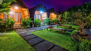 A well-lit garden area with a stone pathway leading to wooden benches and a small pool. - KINTAMANI Paradise - 1BR (Kintamani)