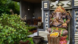 A statue of an elephant deity in a temple setting with a traditional roof and stone architecture. - KINTAMANI Paradise - 1BR (Kintamani)
