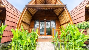 A wooden cabin with a pitched roof, large glass doors, and a stone-paved entrance. - KINTAMANI Paradise - 1BR (Kintamani)