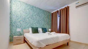 A bedroom with a bed, nightstands, a lamp, and a curtain.