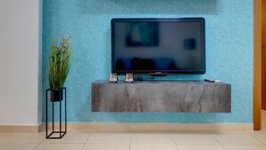 A flat-screen TV mounted on a grey console against a textured blue wall.