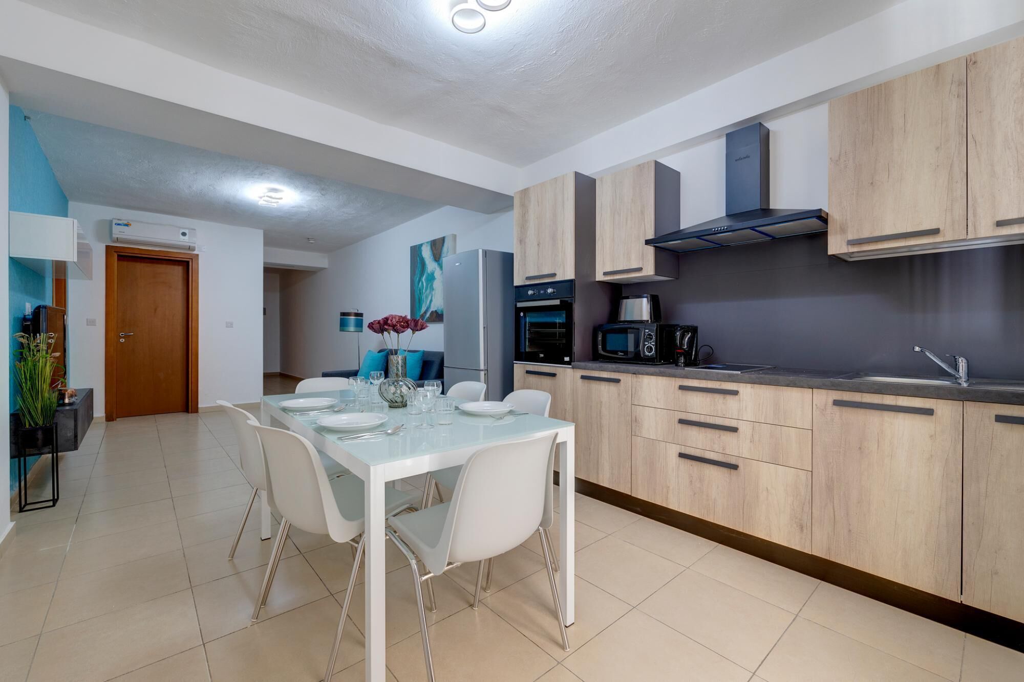 A modern kitchen with wooden cabinets, a built-in oven, microwave, and a stainless steel sink.