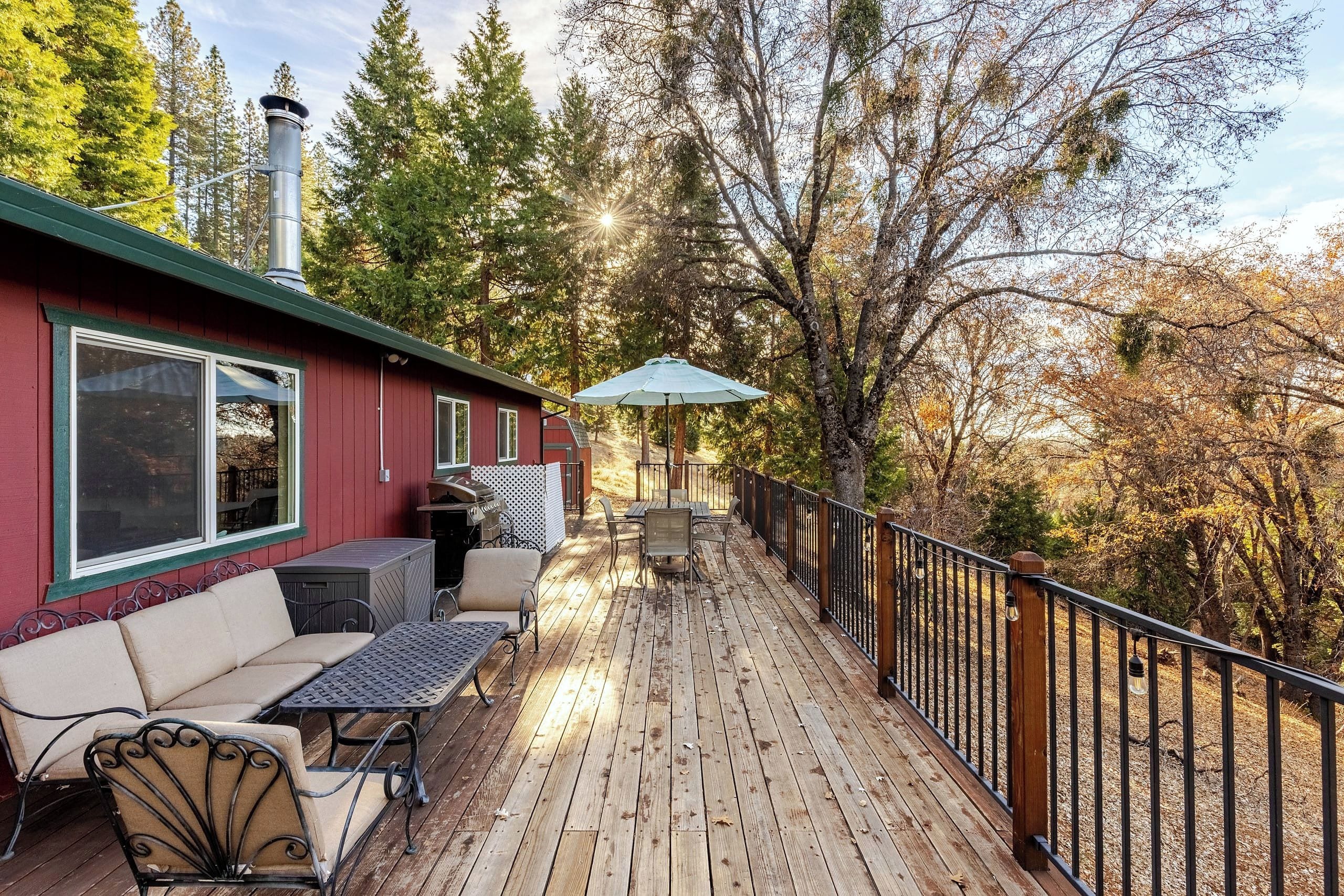 A wooden deck with outdoor furniture, a barbecue grill, and a view of trees.