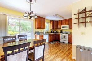 A kitchen with wooden cabinets, a microwave, a stove, and a dining table with chairs.