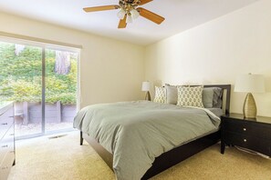 A bedroom with a bed, bedside lamps, a nightstand, and a ceiling fan. - A rejuvenating cabin in the woods (Pioneer)