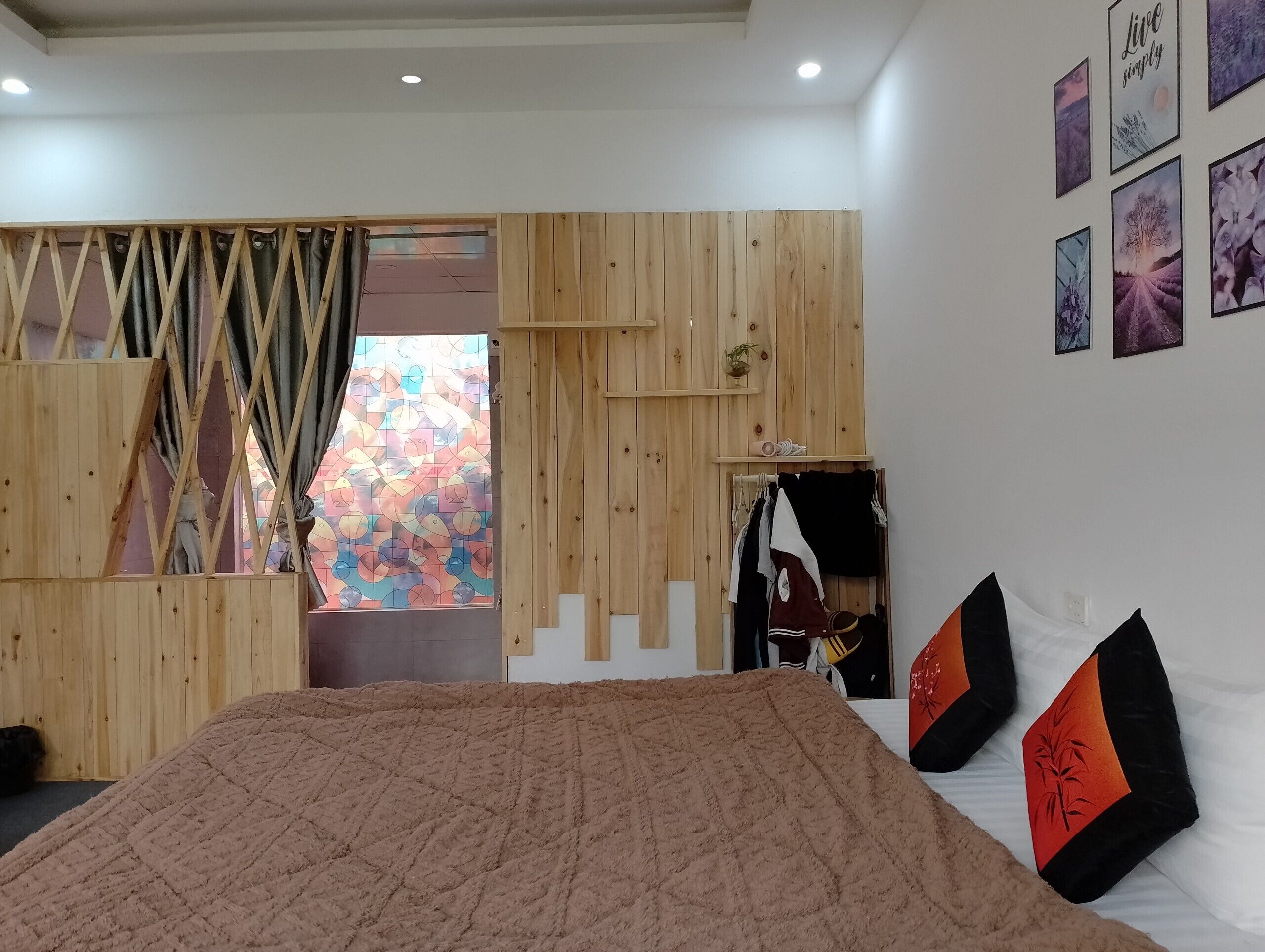 A bedroom with a large bed, wooden panel walls, a wardrobe, and a window with a colorful view.