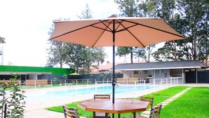 Un espace aménagé au bord de la piscine, avec une table et des chaises en bois, un parasol et une piscine.