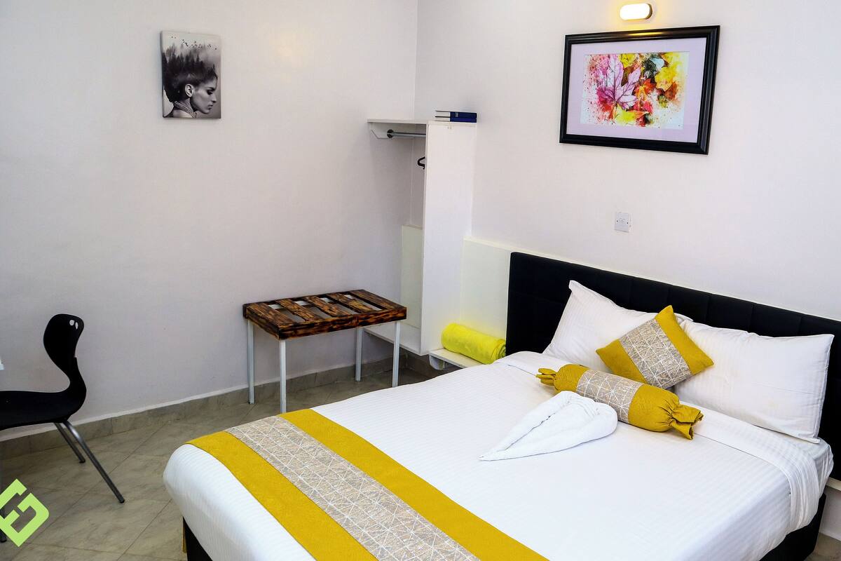 A hotel room with a bed, a chair, a small table, and artwork on the walls.