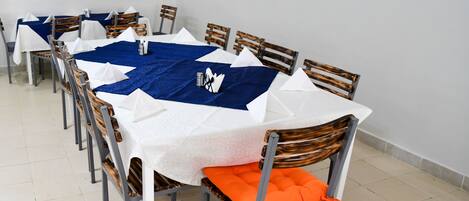 A dining area with a long table, chairs, and a blue table runner.