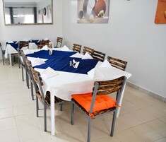 Uma área de refeições com uma mesa comprida, cadeiras e um jogo americano azul.