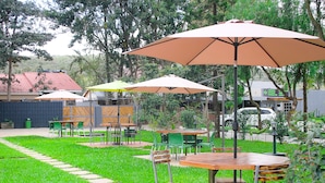 Un espace extérieur aménagé avec des tables et des chaises, entouré de verdure et d’arbres.