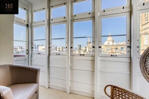 A room with large windows offering a view of a cityscape, including a prominent dome building.