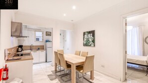 A modern kitchen with a dining area, white walls, and a painting. - Mesmerising Views for a 2BR APT in the Capital ! (Valletta)