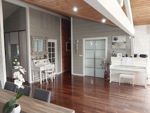A spacious room with a piano, a dining table with chairs, and a mirror with a decorative frame.