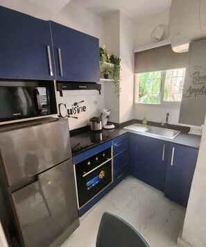 Una cocina moderna con armarios azules, un refrigerador de acero inoxidable, horno empotrado y cafetera.