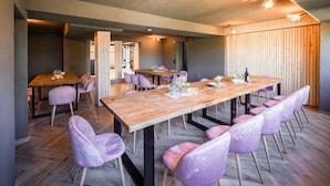 Un espace repas moderne avec une longue table en bois, des chaises à revêtement violet et un mur en bois à lattes.