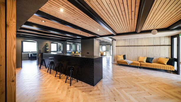 Une cuisine spacieuse dotée d’un îlot central, de planchers en bois et d’un design moderne au niveau du plafond.