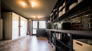 Une cuisine moderne avec un plancher en bois, des meubles de rangement noirs et un four encastré.