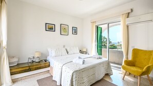 A bedroom with a bed, bedside tables, a chair, and a window with curtains.
