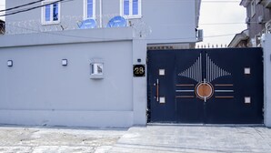 Una entrada cerrada con un letrero con número, una ventana con barrotes y una antena parabólica.