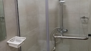 Un vestuario de ducha con paredes de vidrio y tres cabezales de ducha manuales.