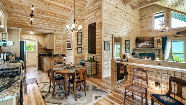 A wooden cabin interior with a dining area, kitchen, and bar.