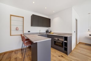 Eine moderne Küche mit Bar, Holzboden und integrierten Geräten.