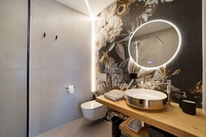 Ein modernes Badezimmer mit Toilette, Waschbecken mit Spiegel und einer blumengeschmückten Wand.