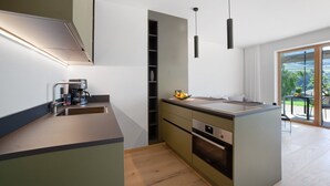 A modern kitchen with a built-in oven, a coffee maker, and a bowl of fruit on the counter. - Studio 'Alivo Living Apartment Olivia' with Mountain View, Shared Terrace and Wi-Fi (Riffian)