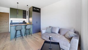 A modern living space with a kitchen area, a sofa, and a coffee table. - Studio 'Alivo Living Apartment Olivia' with Mountain View, Shared Terrace and Wi-Fi (Riffian)