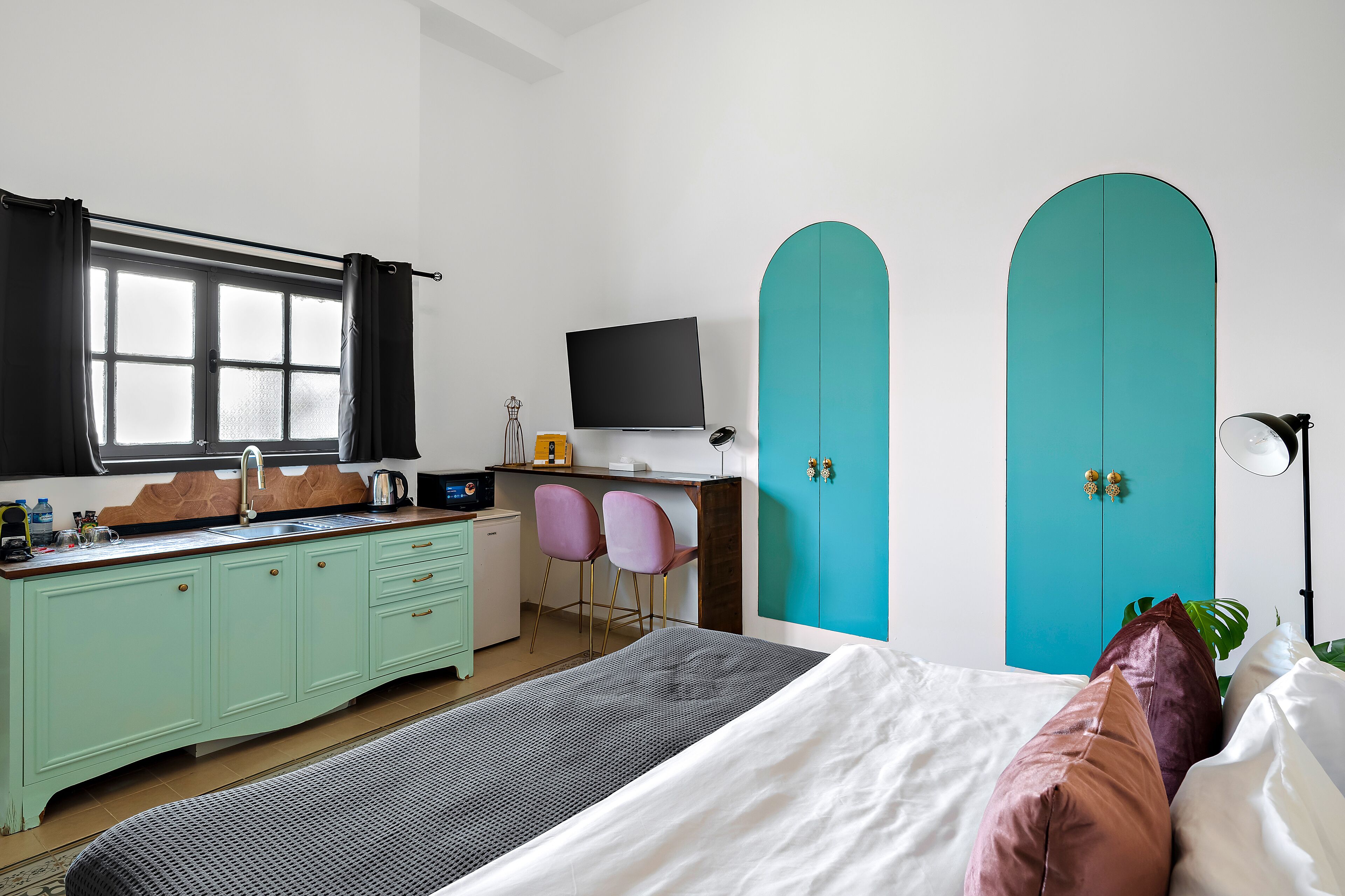 Quarto com cama, escrivaninha, televisão e guarda-roupa.