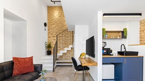 A modern living room with a sofa, coffee table, and a staircase leading to an upper level. - Helios Boutique Suites by La Finca Hotel (Beersheba)