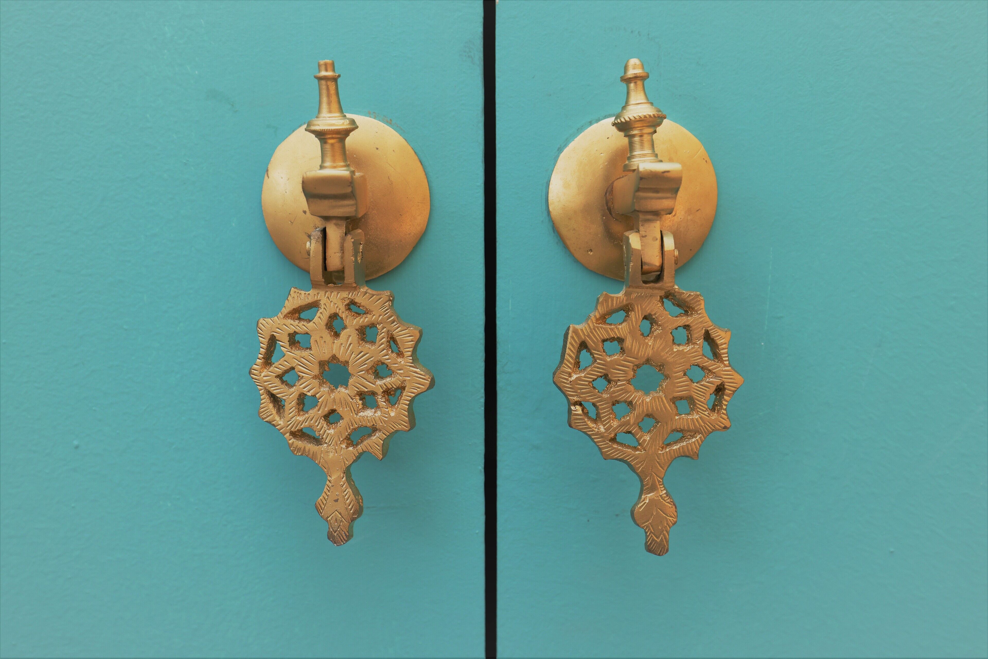 Un par de aretes de bronce ornamentados con un dije circular y un diseño de filigrana detallado.