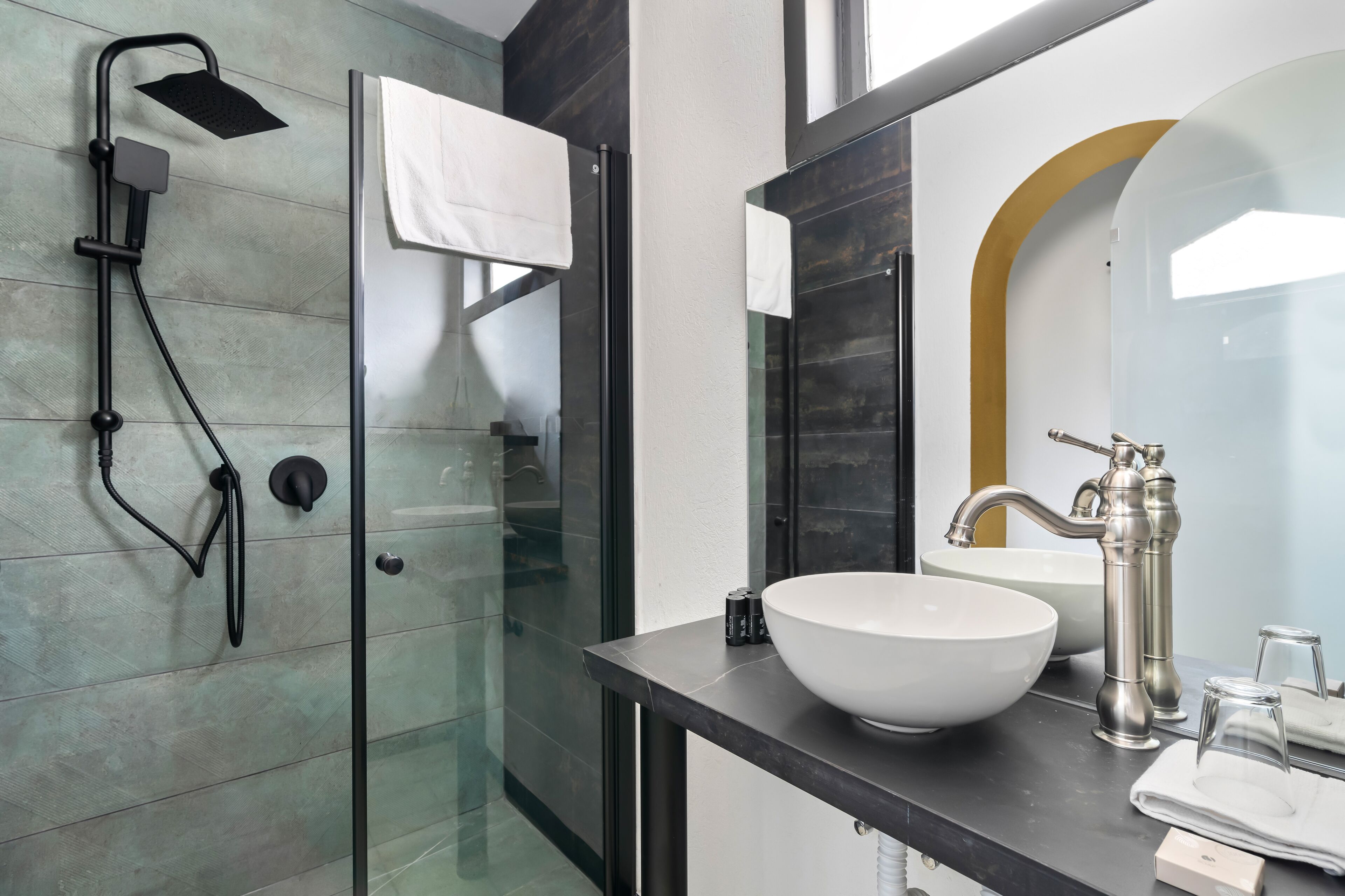 Un bagno moderno con cabina doccia in vetro, un lavabo grande di colore bianco e un rubinetto dal design classico.