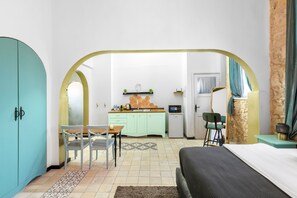 Una habitación compacta con cama, una mesa de comedor con sillas, kitchenette y baño.