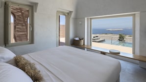 A bedroom with a large bed, a view of the sea, and a balcony with a pool. - Serra Exclusive Suites (Santorini)