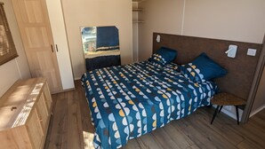 A bedroom with a bed, wooden wardrobe, and a painting on the wall.